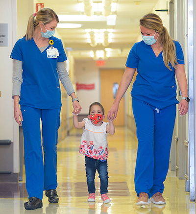 Two providers walking holding hands with a child patient