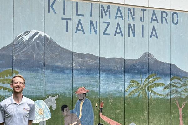 Resident in front of painted sign of mountains in Tanzania