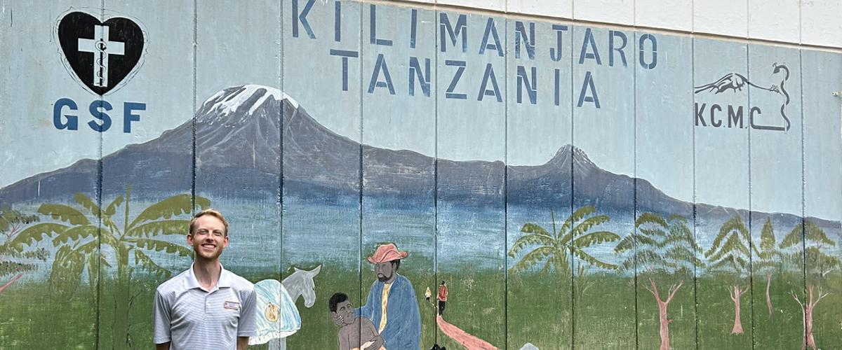 Resident in front of painted sign of mountains in Tanzania