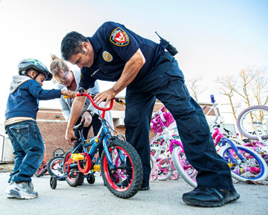 Police officer helping child with bicycle